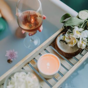 A serene bath setting with wine, candles, and flowers for a relaxing spa experience.